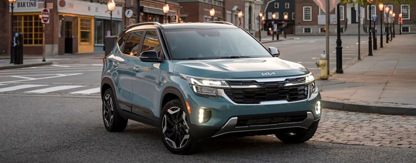 A light blue 2025 Kia Seltos SX driving in a downtown area.